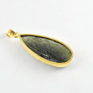 Op de afbeelding: Een gouden hanger met een traanvormige groene steen. De steen heeft een marmerpatroon en is gezet in een gouden bezel.