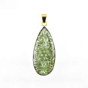 Op de afbeelding: Een groene edelsteen hanger met een gegraveerd bloemenmotief, gezet in goud.