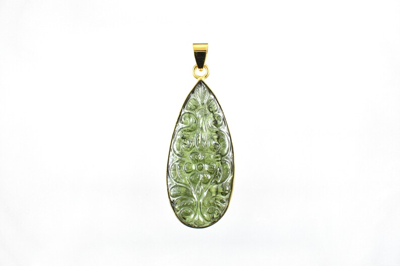 Op de afbeelding: Een groene edelsteen hanger met een gegraveerd bloemenmotief, gezet in goud.