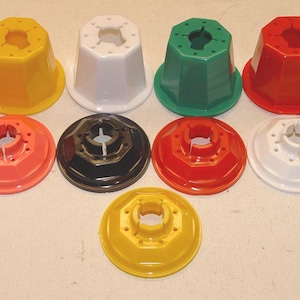 May include: A collection of thirteen plastic, octagonal-shaped components in various colors including red, yellow, white, green, black, orange, and purple. The set consists of six taller, cup-like pieces and seven flatter, disc-like base pieces.