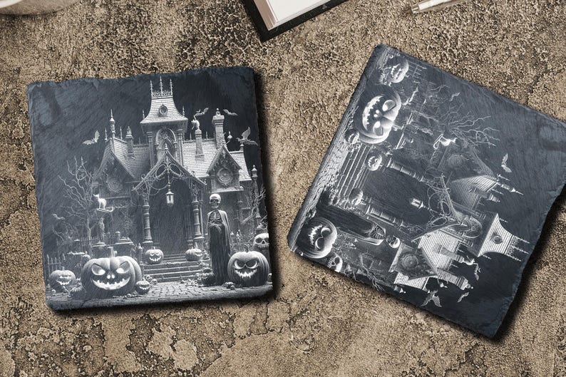 May include: Two black slate coasters with a Halloween theme. One coaster features a spooky house with a figure in front of it and pumpkins. The other coaster features a spooky house with pumpkins and bats.