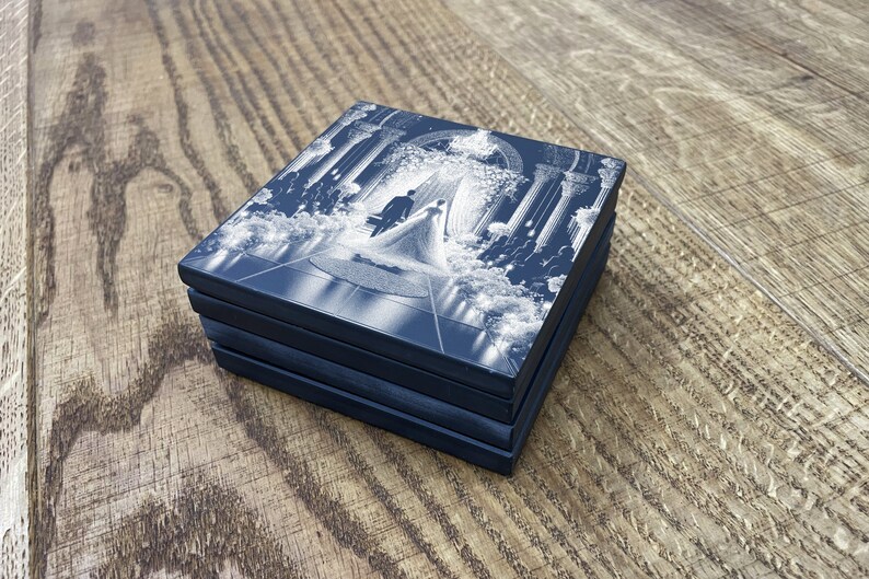 May include: A set of four blue square coasters with a white design of a wedding ceremony. The design features a bride and groom walking down the aisle.