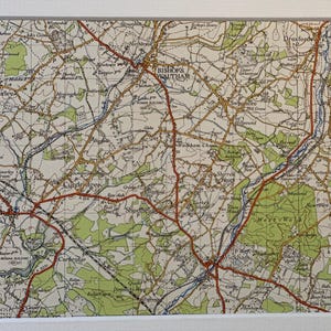 Peut inclure: Une carte vintage encadrée représentant une zone rurale détaillée, avec des routes rouges et des noms de lieux tels que Bishop's Waltham et Curdridge. Des zones vertes indiquent des forêts ou des parcs. La carte est encadrée de blanc.