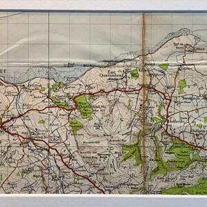 Peut inclure: Une carte vintage des collines de Quantock dans le Somerset, en Angleterre. La carte montre les villes de Watchet, Williton, Bicknoller, East Quantoxhead, Kilton, Stringston, Holford et Dodington. La carte est imprimée en noir et blanc avec des lignes rouges et vertes.