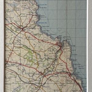 May include: A vintage map of the St. Abb's Head and Eyemouth area in Scotland. The map shows the coastline, towns, and surrounding countryside. The map is printed on a cream-colored paper with brown and red lines.