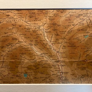 May include: An antique map of the Lake District in England, showing the location of various mountains, rivers, and towns. The map is printed on a brown paper with a faded, vintage look. The map is titled "LANCASHIRE & WESTMORLAND" and "CHEST."