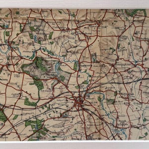 May include: An antique map of the English countryside, featuring a network of roads and rivers. The map is printed on cream-coloured paper with brown and red lines, and green areas representing forests and fields. The map includes the names of towns and villages, such as Layham, Blackding, and Banninghams.
