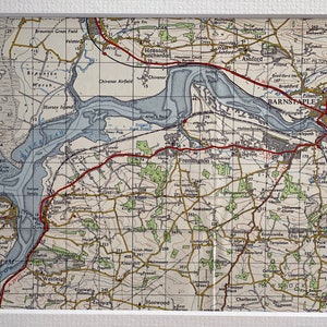 May include: A vintage map of the Barnstaple area in Devon, England. The map shows the town of Barnstaple, the River Taw, and surrounding villages. The map is printed in black, red, and blue ink on a white background.
