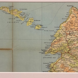 May include: A vintage map print featuring the Aran Islands and the western coast of Ireland. The map uses a muted color palette of beige, yellow, and blue, with detailed geographical features and place names. The print is framed in a white border.