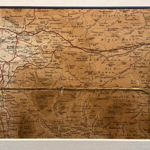 May include: An antique map of the English countryside, featuring the names of various moors and towns. The map is printed on aged paper with a brown and cream color scheme. The map is folded in half, with a crease running down the center.