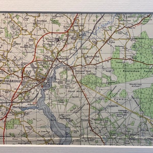 May include: A vintage map of the Woodbridge area in Suffolk, England. The map shows the town of Woodbridge, the River Deben, and surrounding villages. The map is printed in black, brown, and green on a white background. The map is titled "Woodbridge" and includes the text "Rendlesham Forest" and "Sutton Common".