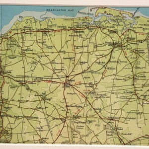 Könnte beinhalten: Gerahmte Vintage-Karte einer Küstenregion mit detaillierten Straßennetzen, Städten und geografischen Merkmalen. Die Karte hat eine Farbpalette aus Beige, Grün und Blau, mit Ortsnamen und Straßen.