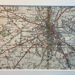 Könnte beinhalten: Eine Vintage-Karte von Derby, England, mit roten Straßen und Flüssen und dem Text "DERBY" in der Mitte.