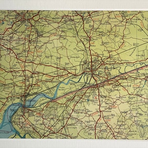Puede incluir: Un mapa vintage de la zona alrededor de la ciudad de Warrington, Inglaterra. El mapa está impreso sobre un fondo amarillo claro con líneas rojas que indican carreteras y ríos. El mapa incluye los nombres de ciudades, pueblos y puntos de referencia.