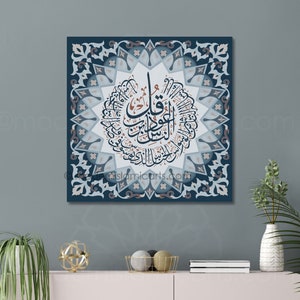 May include: A square canvas print with a blue background and intricate white and grey floral patterns. The centre of the print features a circular design with Arabic calligraphy in brown and white.