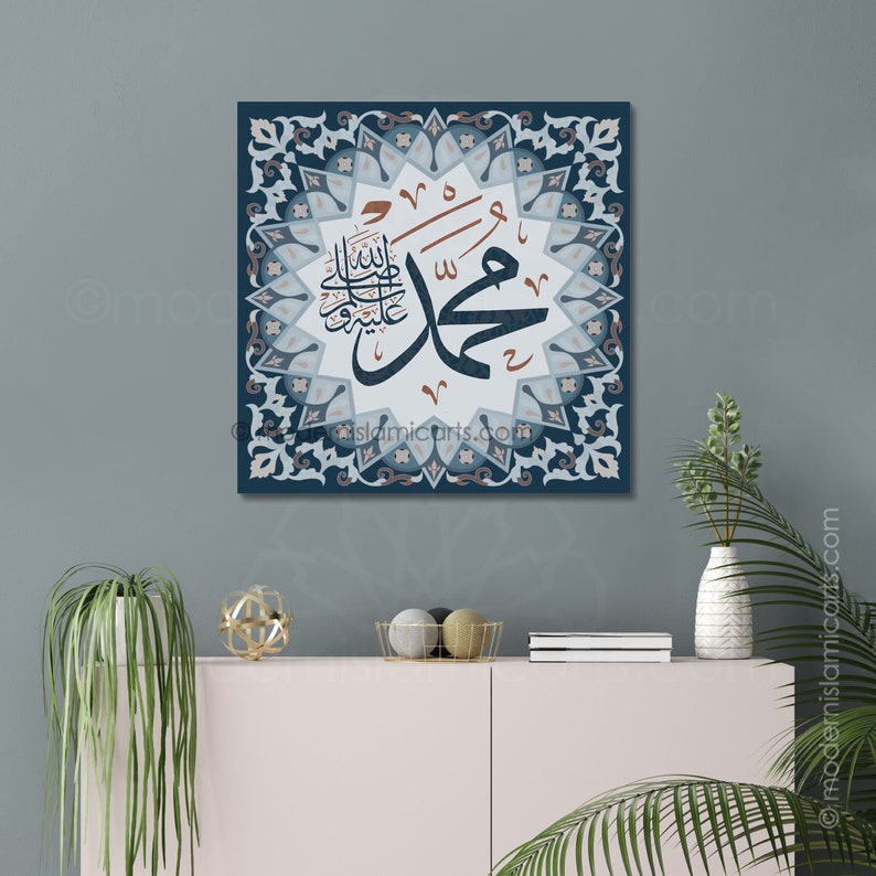 May include: A square canvas print with a blue background and intricate white and grey floral patterns. The centre features a large, white Arabic calligraphy inscription in brown and black, surrounded by a white starburst. The inscription reads "Muhammad, the Messenger of Allah".