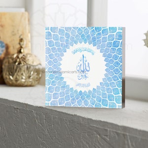 May include: A blue and white square wall decor with an intricate design of repeating leaf shapes. The center of the design features a white circle with Arabic calligraphy in black.