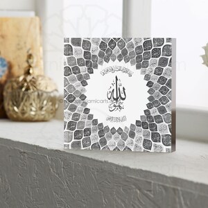May include: A square, clear acrylic block with a black and white design. The design features a circular pattern of leaves with the word "Allah" written in Arabic calligraphy in the center.