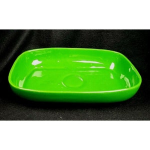 May include: A bright green ceramic serving dish with a rectangular shape and slightly rounded edges. The dish has a smooth, glossy finish.