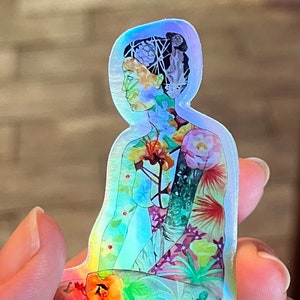 May include: Holographic sticker featuring a seated figure with a floral design overlay. The figure's head and body are filled with colorful flowers and foliage. The sticker has a rainbow sheen, reflecting various colors.