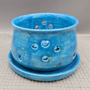 Könnte beinhalten: Eine blaue Keramikschüssel mit gesprenkeltem Glase und herzförmigen Ausschnitten. Die Schüssel hat eine passende Untertasse.