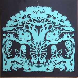 Puede incluir: Una obra de arte en papel recortado con un diseño simétrico de un árbol con una copa y un tronco detallados. El árbol está rodeado de figuras de animales estilizadas y follaje, todo en color verde azulado claro sobre un fondo negro.