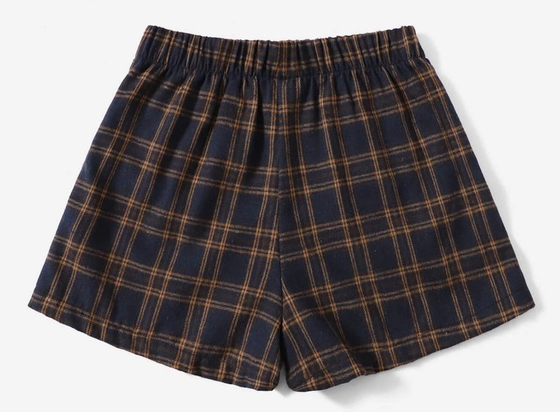 K&ouml;nnte beinhalten: Marineblaue und braune Shorts mit Karomuster und elastischem Bund. Die Shorts haben ein klassisches Karomuster in einem dunkelblauen und braunen Farbschema. Die Shorts sind aus einem weichen, bequemen Material gefertigt.