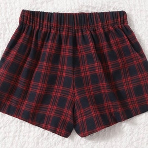 K&ouml;nnte beinhalten: Rot-marine karierte Shorts mit elastischem Bund. Die Shorts haben ein klassisches Karomuster mit einem sich wiederholenden Gitter aus roten Linien auf marineblauem Hintergrund. Die Shorts sind aus einem weichen, bequemen Stoff gefertigt.