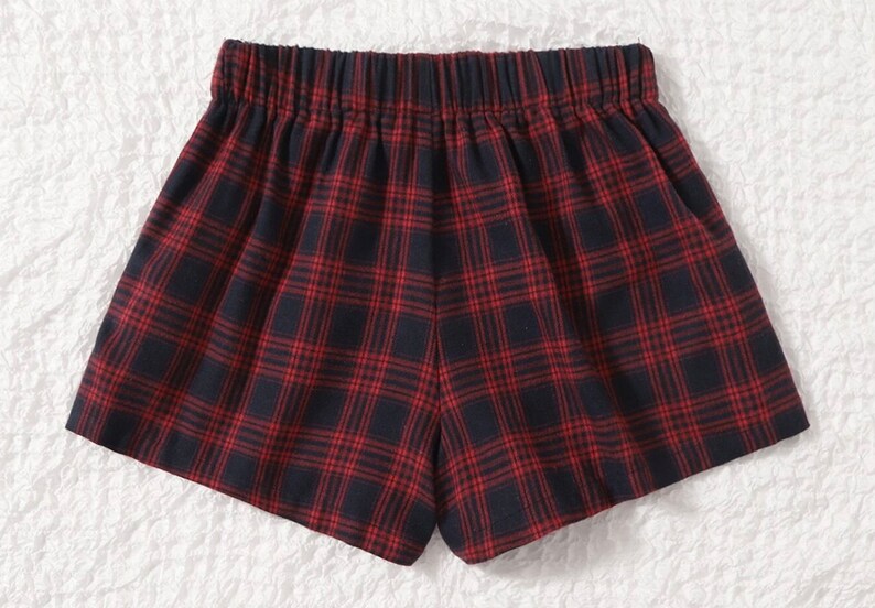 K&ouml;nnte beinhalten: Rot-marine karierte Shorts mit elastischem Bund. Die Shorts haben ein klassisches Karomuster mit einem sich wiederholenden Gitter aus roten Linien auf marineblauem Hintergrund. Die Shorts sind aus einem weichen, bequemen Stoff gefertigt.