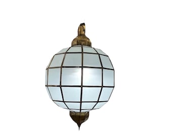 May include: A spherical pendant light fixture with a geometric design. The light has a pale blue glass globe encased in a dark metal frame. The top and bottom are adorned with ornate brass-colored metal accents.