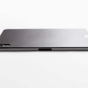May include: A sleek, silver-coloured tablet computer with a black camera lens and a black power button on the side.