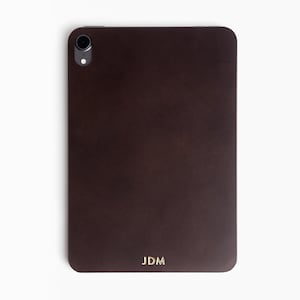 May include: A dark brown leather case for a tablet with a camera cutout and the initials "JDM" embossed in gold.