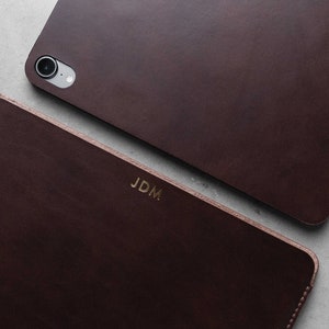 May include: Two brown leather cases with the initials "JDM" embossed in gold on the front. The case on the top has a camera cutout.