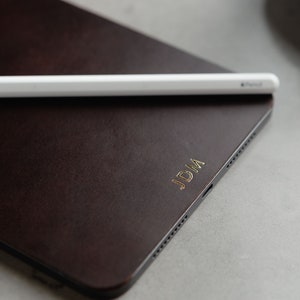 May include: A brown leather iPad case with the initials "JDM" embossed in gold.