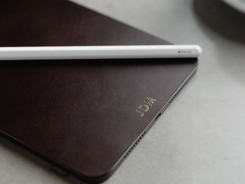 May include: A brown leather iPad case with the initials "JDM" embossed in gold.