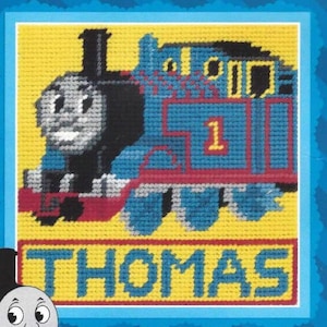 May include: A blue and red toy train with a smiling face and the number 1 on the side. The train is on a yellow background with the word "THOMAS" written below it.