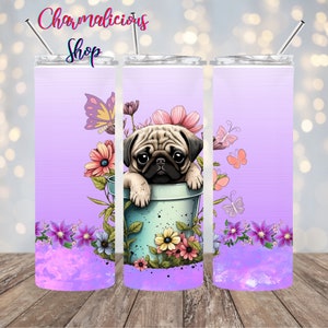 Puede incluir: Un vaso con un diseño de pug. El vaso presenta un fondo morado claro con un efecto de acuarela en la parte inferior. Un pug está dentro de una maceta azul rodeado de flores y mariposas. El texto "Charmalicious Shop" está en la parte superior.