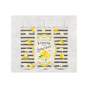 Pu&ograve; includere: Tre bicchieri in acciaio inossidabile con cannucce. I bicchieri presentano un design di limoni gialli, fiori bianchi e strisce nere su sfondo beige. Il bicchiere centrale ha il testo "When life gives you lemons make lemonade, freshly squeezed."