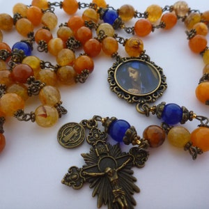 Rosary of Our Lady of Sorrows (5 decades) 8mm fire agate, 8mm blue glass. Caps, spacers. St Benedict charm, medallion, crucifix.