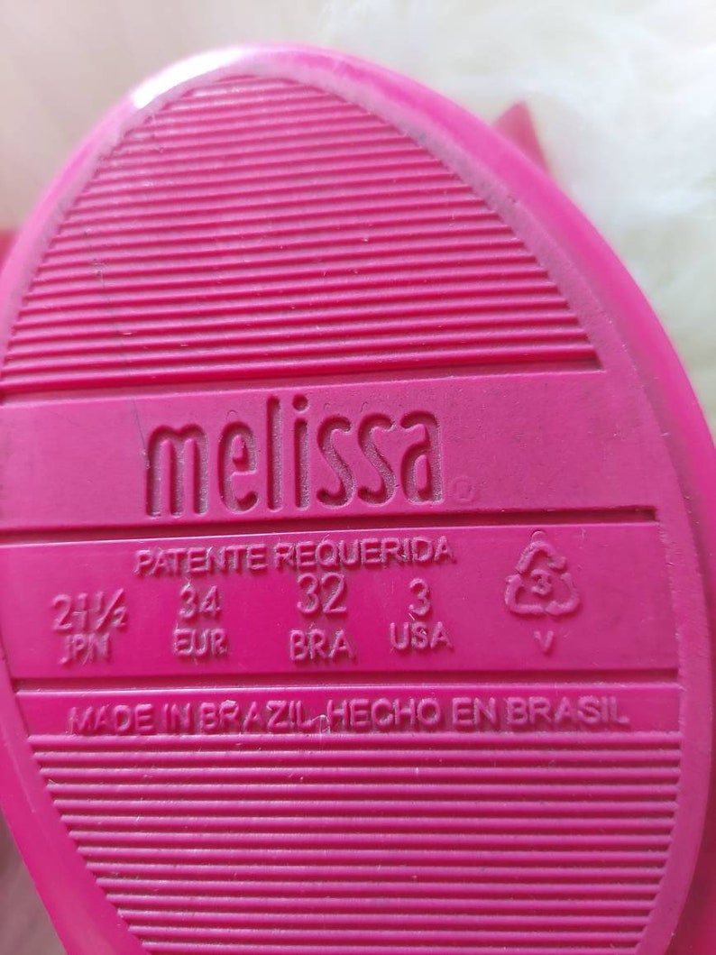 May include: Pink Melissa brand shoe sole with size information in Japanese, European, Brazilian, and US sizing. The text reads "Patente Requerida" and "Made in Brazil Hecho en Brasil".