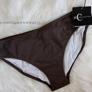 May include: A brown bikini bottom with a white lining. The bikini bottom has a tag attached that says "The C Collection".