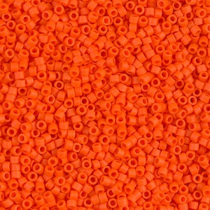 May include: A close-up image of a large quantity of small, bright orange round seed beads. The beads are all the same size and shape, and they are arranged in a random pattern.