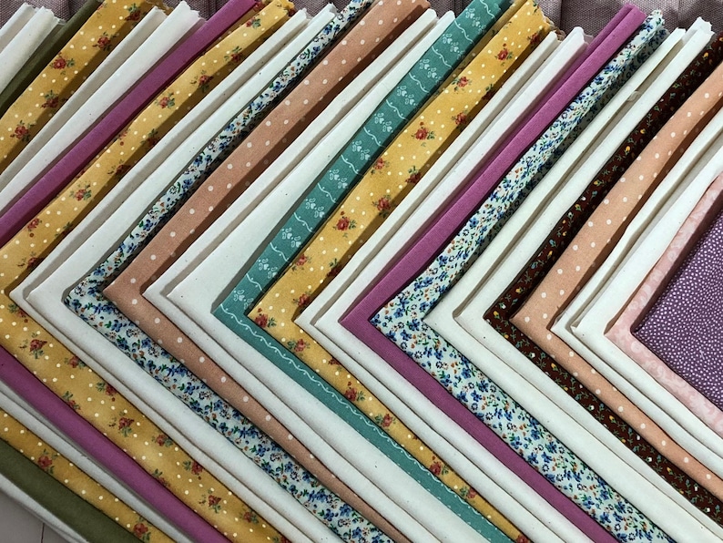 May include: A stack of fabric squares in various colors and patterns, including floral, polka dot, and solid colors. The fabric squares are arranged in a diagonal pattern.