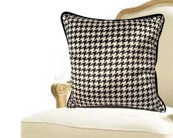 May include: A white armchair with a black and white houndstooth patterned pillow. The chair has a carved wooden frame and legs.