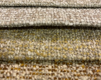 Op de afbeelding: Close-up van vijf stofstalen in verschillende tinten beige, bruin en geel. De stof heeft een textuur en is geweven.