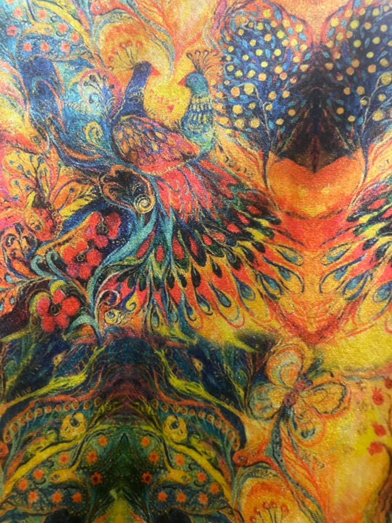 Op de afbeelding: Een kleurrijke stof met een pauwenmotief. De stof heeft twee pauwen met blauwe en groene veren, een vlinder en bloemmotieven in tinten rood, oranje, geel en groen.