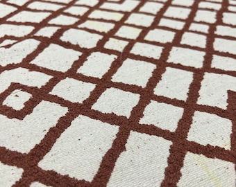 May include: White fabric with a brown geometric pattern of squares and diamonds. The pattern is raised and textured.
