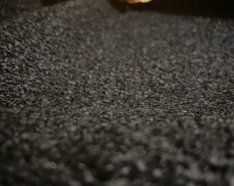 May include: Close-up of a black fuzzy fabric with a soft texture.