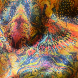 Op de afbeelding: Een kleurrijke stof met een paisley-patroon met pauwen in tinten blauw, geel, oranje en rood.