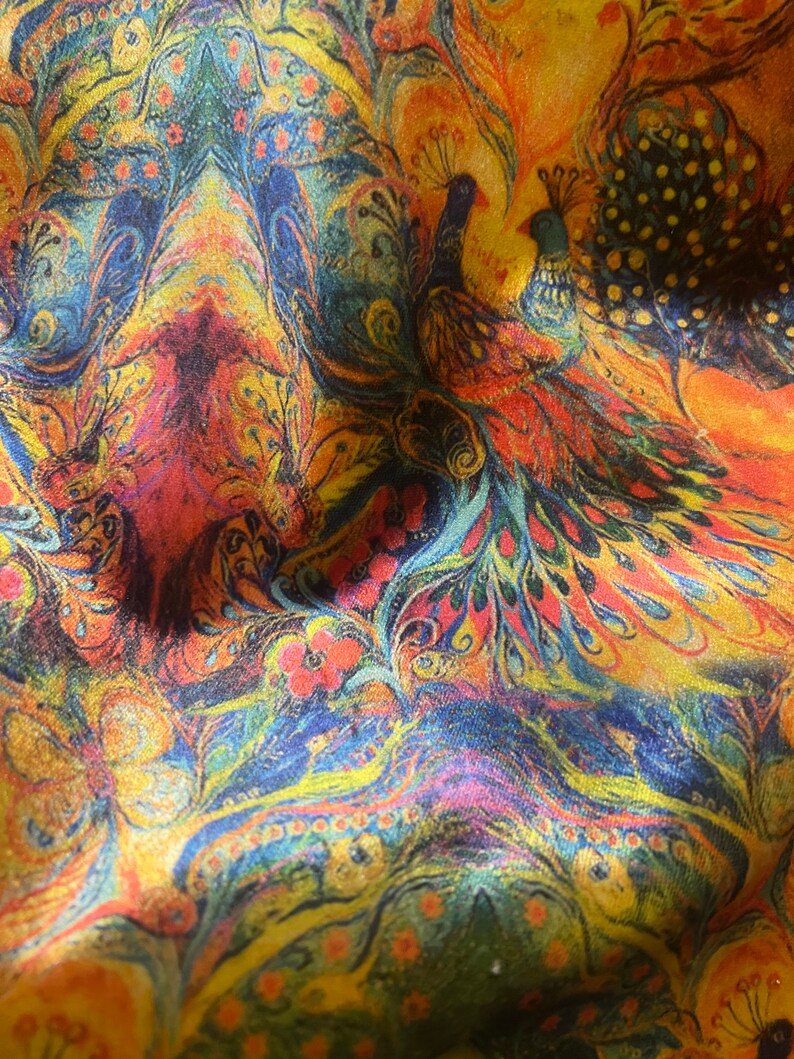 Op de afbeelding: Een kleurrijke stof met een paisley-patroon met pauwen in tinten blauw, geel, oranje en rood.